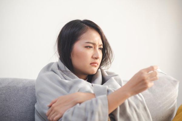 Attractive young woman using a thermometer to measure fever